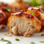 Golden honey chipotle chicken skewers on a white ceramic plate, garnished with fresh cilantro and a small bowl of chipotle sauce on the side, bright natural light on a clean white table.
