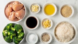 lat lay overhead shot of all Easy Chicken and Broccoli Stir Fry ingredients arranged in small white bowls on a clean white marble table in bright natural light