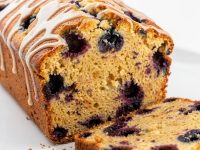 Sliced lemon blueberry bread arranged in an overhead flat lay on a white plate.