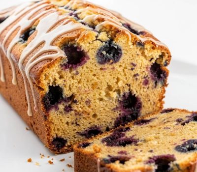 Sliced lemon blueberry bread arranged in an overhead flat lay on a white plate.
