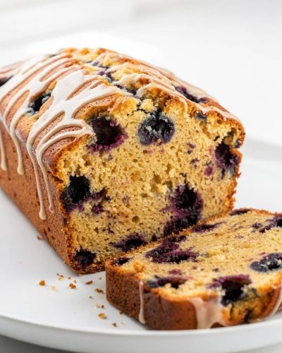 Sliced lemon blueberry bread arranged in an overhead flat lay on a white plate.