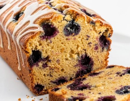 Sliced lemon blueberry bread arranged in an overhead flat lay on a white plate.