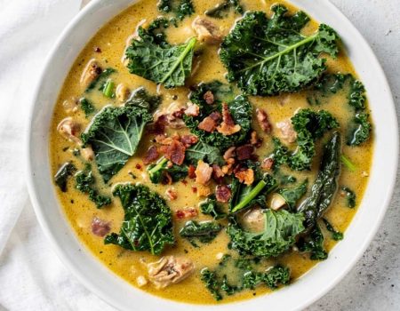 Zuppa Toscana recipe served in a white ceramic bowl overhead flat lay, creamy golden soup with Italian sausage, kale, and crumbled bacon, Parmesan cheese on the side, white marble table, natural daylight