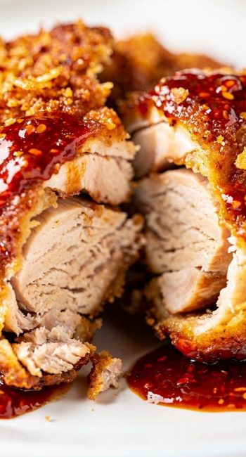 Close-up of Crispy Gochujang Chicken showing the juicy interior and crisp golden coating covered in red gochujang sauce.