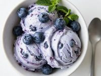 Overhead shot of blueberry frozen yogurt in a white bowl with fresh berries.