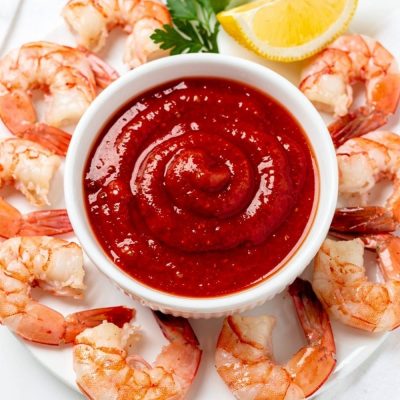 Best homemade cocktail sauce recipe in white ceramic bowl with fresh shrimp on bright white table