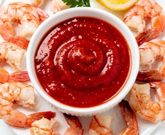 Best homemade cocktail sauce recipe in white ceramic bowl with fresh shrimp on bright white table