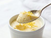 Overhead shot of lemon posset in glass ramekins on a white table.