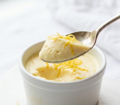 Overhead shot of lemon posset in glass ramekins on a white table.