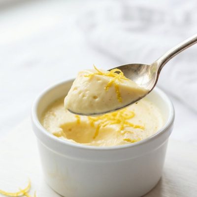 Overhead shot of lemon posset in glass ramekins on a white table.
