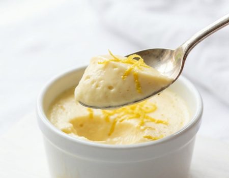 Overhead shot of lemon posset in glass ramekins on a white table.