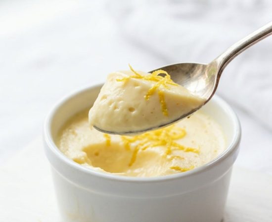 Overhead shot of lemon posset in glass ramekins on a white table.