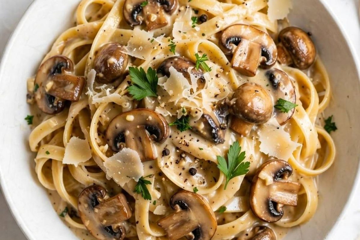 Overhead view of creamy date night mushroom fettuccine with mushrooms, Parmesan, and parsley on a white table.