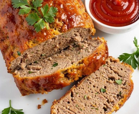 Styled lifestyle food photography of The Best Turkey Meatloaf Recipe served on a white marble table, surrounded by fresh parsley, a small bowl of ketchup glaze, and a side of creamy mashed potatoes, bright airy natural afternoon light, no shadows, no smoke, clean white table, minimal styling, food blog photography style