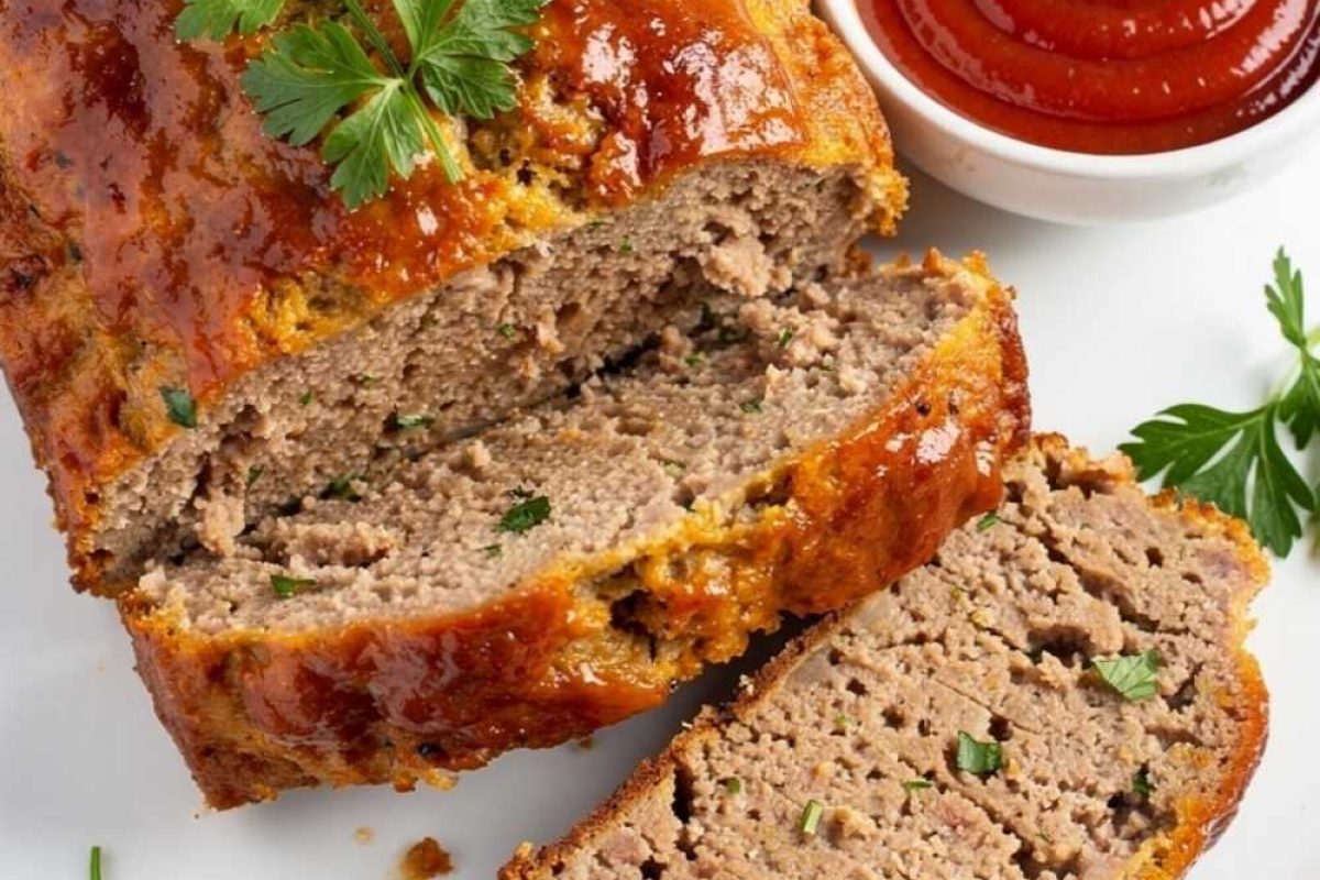 Styled lifestyle food photography of The Best Turkey Meatloaf Recipe served on a white marble table, surrounded by fresh parsley, a small bowl of ketchup glaze, and a side of creamy mashed potatoes, bright airy natural afternoon light, no shadows, no smoke, clean white table, minimal styling, food blog photography style