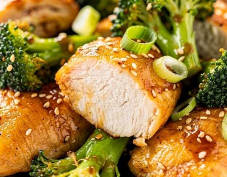 Close-up macro shot of easy chicken and broccoli stir fry showing golden chicken interior and bright green broccoli with glossy sauce, sesame seeds visible.