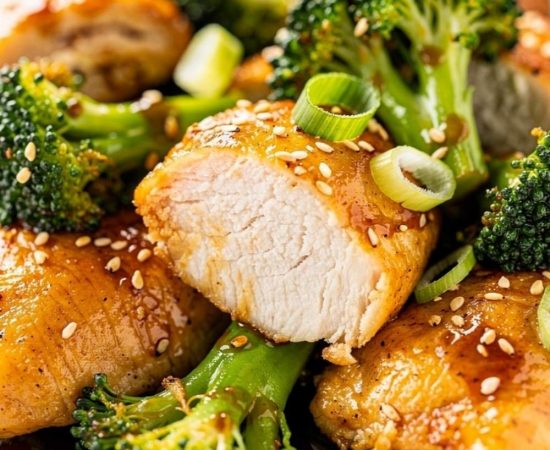 Close-up macro shot of easy chicken and broccoli stir fry showing golden chicken interior and bright green broccoli with glossy sauce, sesame seeds visible.
