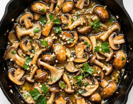garlic butter mushrooms in a skillet with parsley and glossy butter sauce.