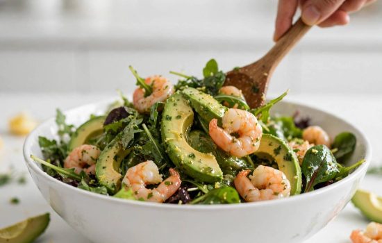 Gently folding shrimp and avocado into a dressed shrimp and avocado salad.