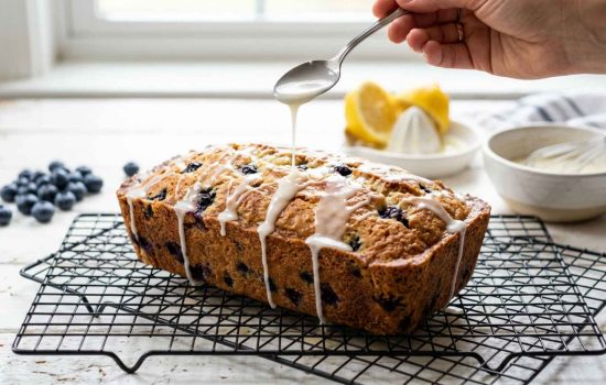 Golden baked lemon blueberry bread cooling with lemon glaze drizzle.
