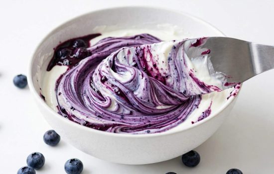 Folding blueberry puree into plain yogurt.