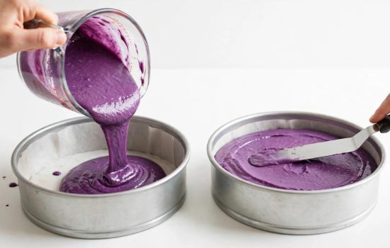 Pouring purple velvet batter into cake pans