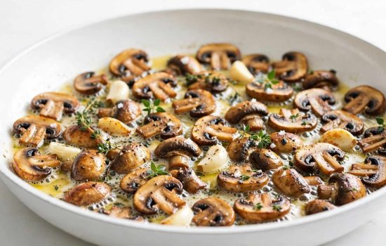 Mushrooms and garlic browning in butter in a skillet for mushroom fettuccine.
