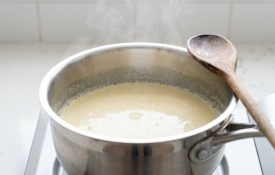 Cream and sugar mixture gently simmering with light steam in a saucepan.