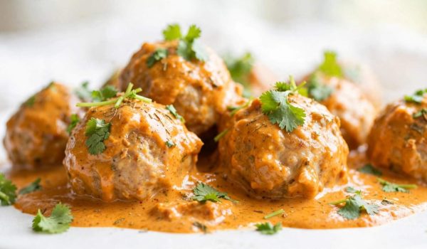 Close-up of tender butter chicken meatballs coated in creamy tomato gravy.