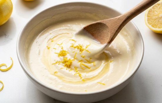 Fresh lemon juice and zest being stirred into warm cream mixture.