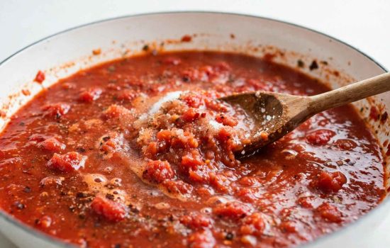 Simmering crushed tomatoes and spices to build butter chicken meatball sauce.