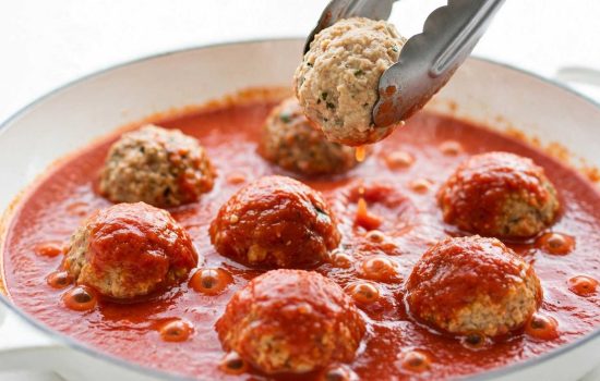 Adding cooked meatballs to creamy butter chicken tomato sauce.