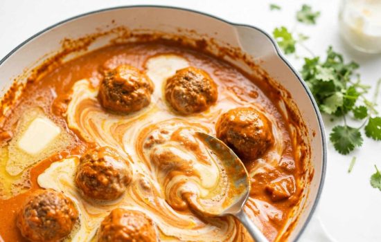 Stirring butter and cream into butter chicken meatball sauce for a silky finish.