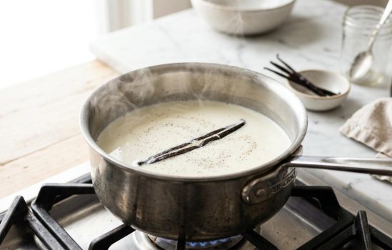 Whole milk and heavy cream warming with a vanilla bean in a saucepan.