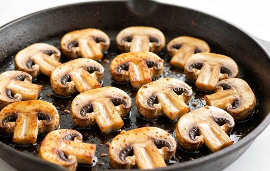 Mushrooms searing in a single layer in a hot skillet