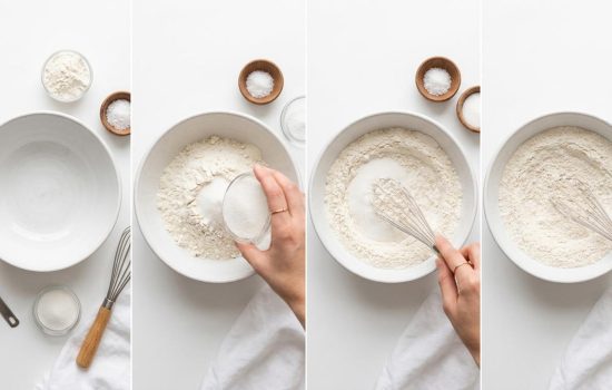 Flour, salt, and sugar being mixed together in a white bowl.