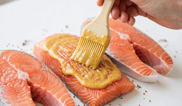 Brushing honey mustard glaze onto salmon fillets with a silicone brush