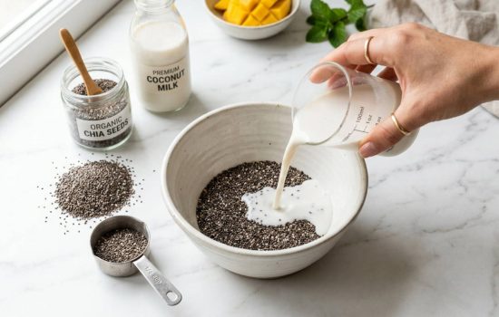 Measuring chia seeds and coconut milk into a mixing bowl